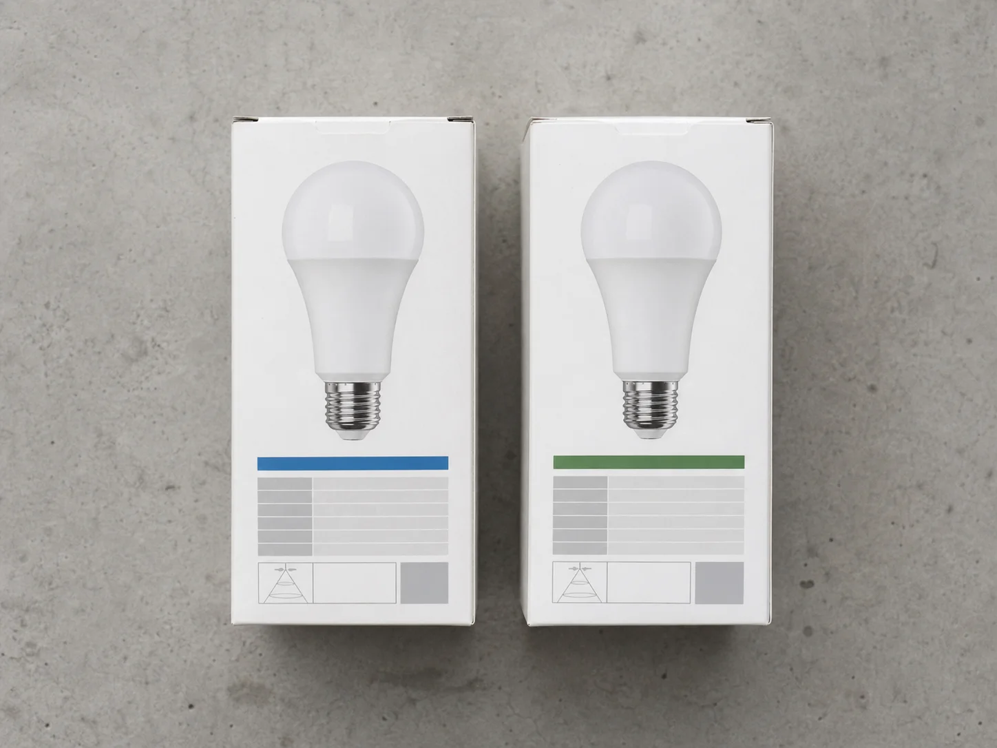 Zwei LED-Lampen-Verpackungen nebeneinander auf neutralem Beton-Hintergrund mit minimal unterschiedlichen Spezifikations-Labels
