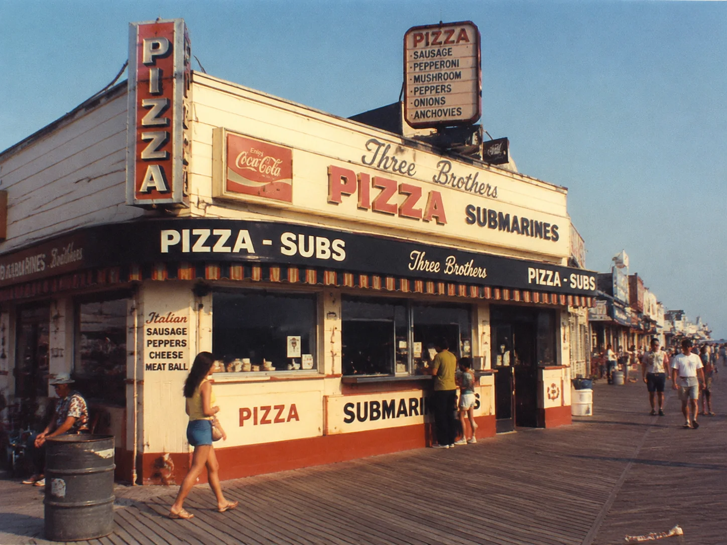 Alter amerikanischer Jersey-Shore-Boardwalk Pizza-und-Sub-Shop in 1970er-Ästhetik mit Vintage-Beschilderung, warme nostalgische Töne