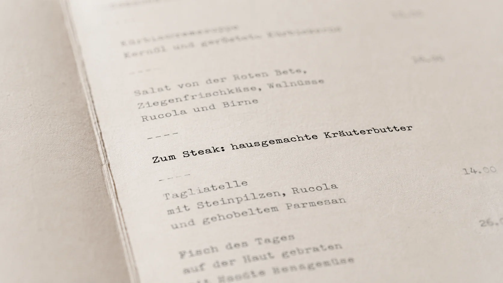 Aufgeschlagene Speisekarte mit Schreibmaschinen-Typografie auf weissem Marmortisch, ein Hauptgericht ist mit rotem Stift handschriftlich umkreist mit Randnotiz Kraeuterbutter
